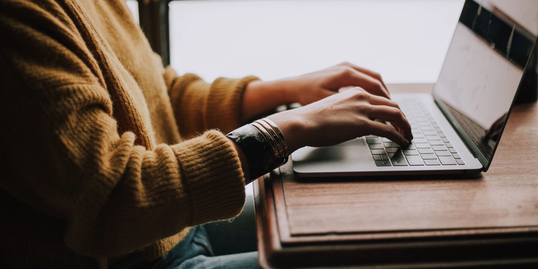 Hands typing on a laptop at a table.