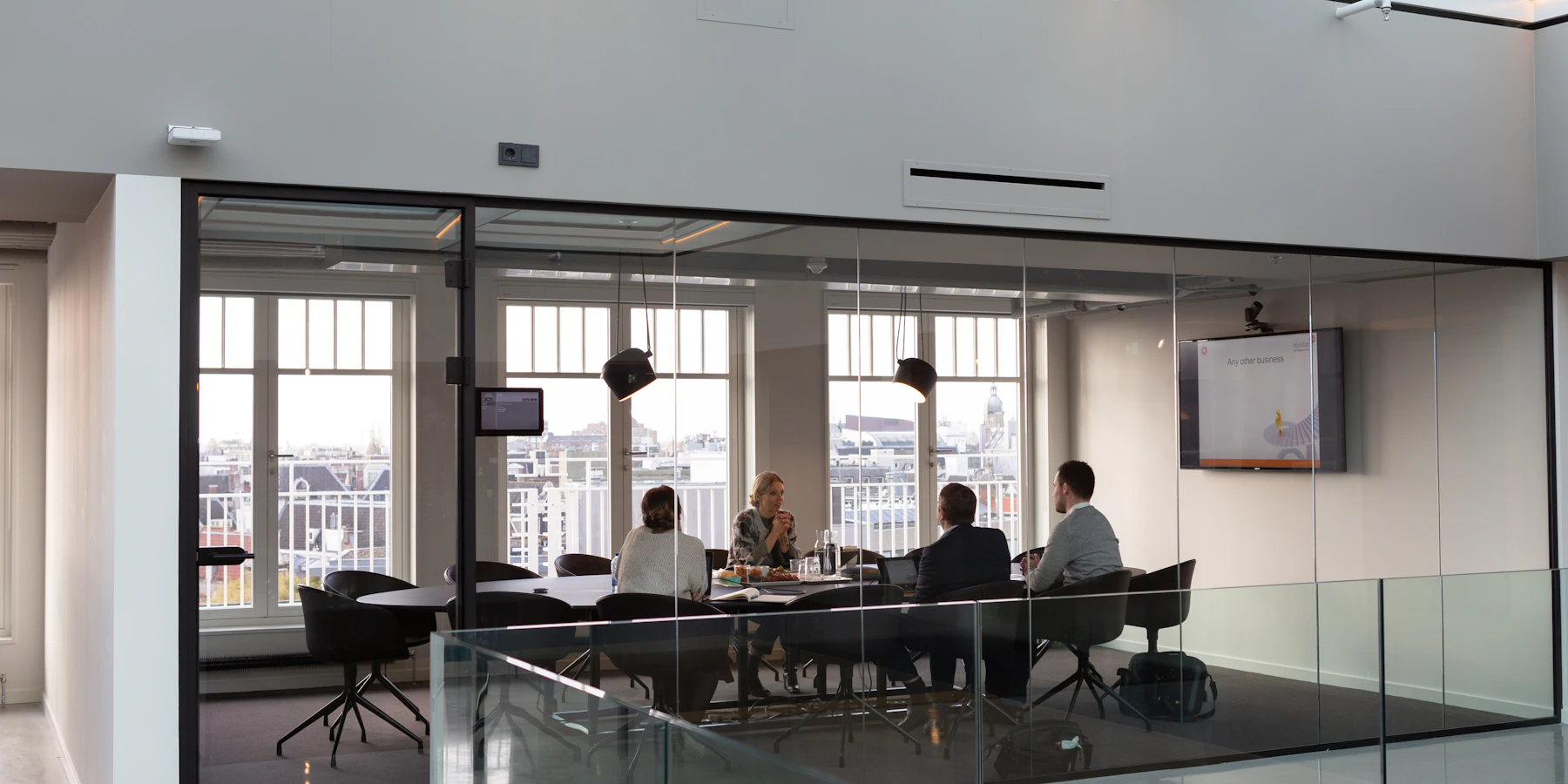 Colleagues meeting in a glass-walled Amsterdam office.
