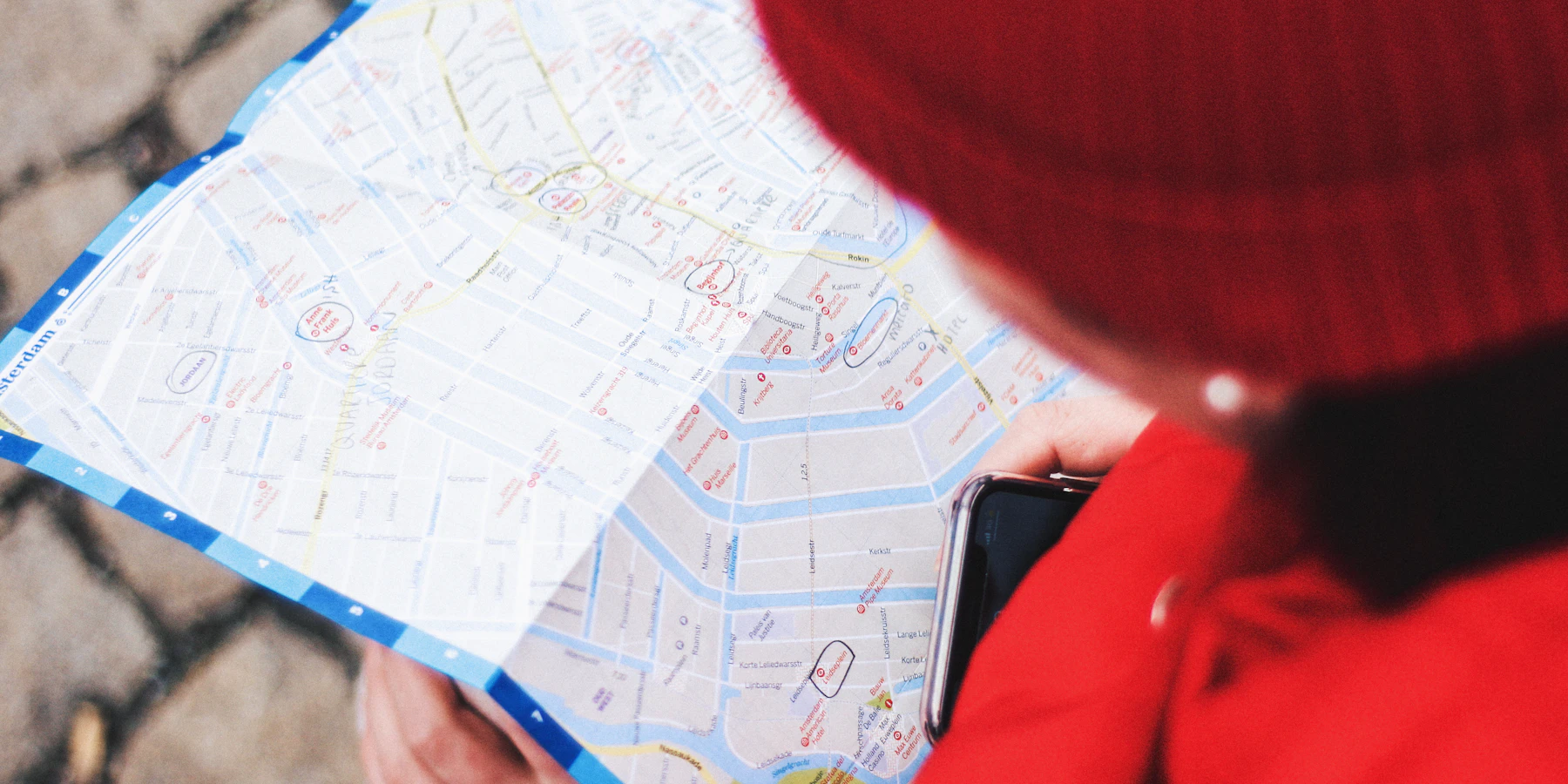 An Amsterdam city map held by a visitor beside a phone.